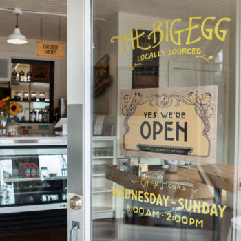 Hand painted sign on front door along with interior of The Big Egg breakfast and brunch cafe